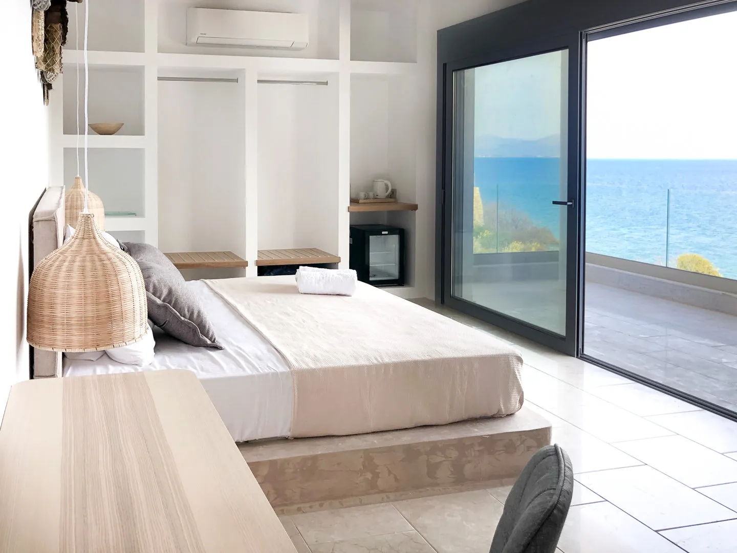 Zephyros-Schlafzimmer mit Kingsize-Bett auf Steinpodest und Zugang zur Terrasse mit Meerblick