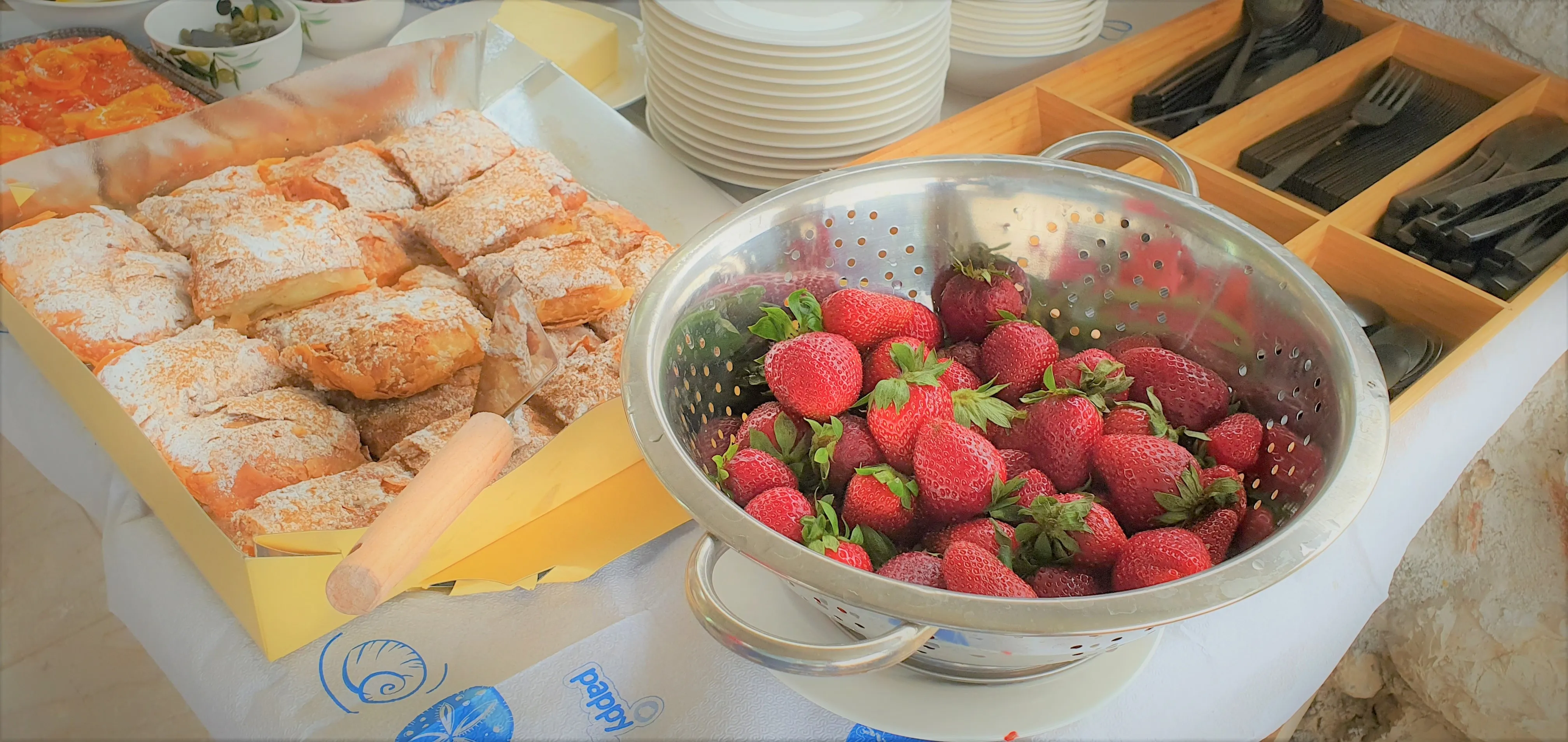 Frische Erdbeeren und Frühstücksgerichte auf dem Tisch im Freien