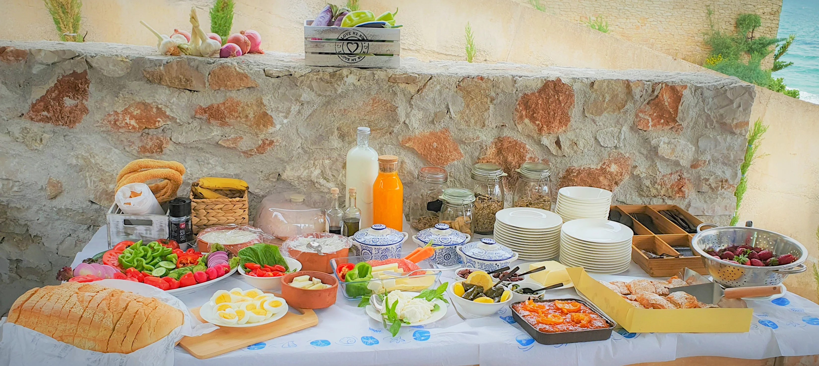 Frühstücksbuffet mit Obst, Eiern und regionalen Produkten vor der Steinmauer