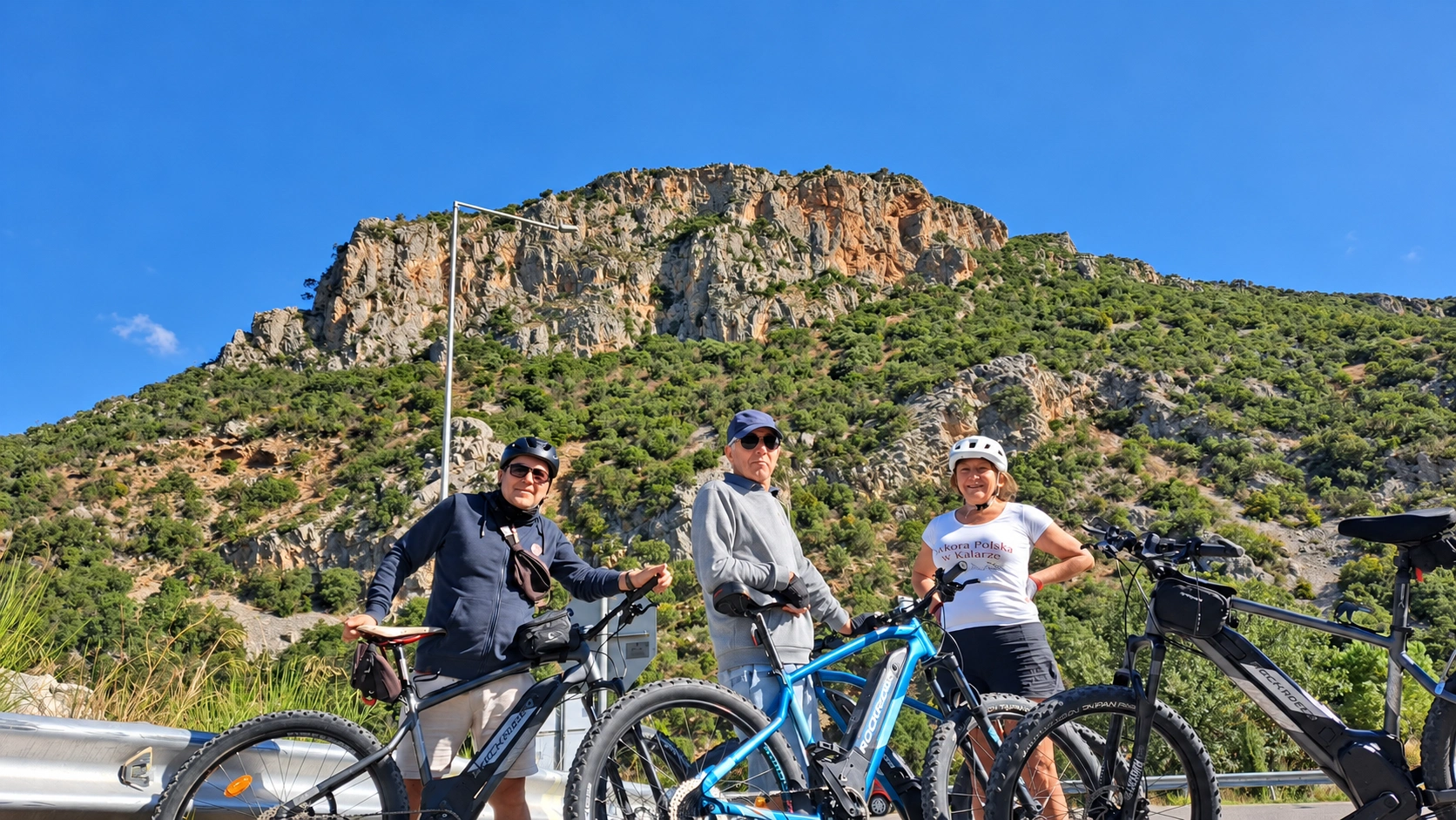 Three cyclists below a rocky hillside in the Peloponnese